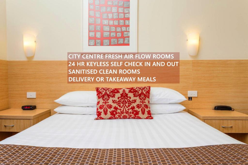 沃加沃加俱乐部汽车旅馆和公寓的一间卧室配有一张红色枕头的床