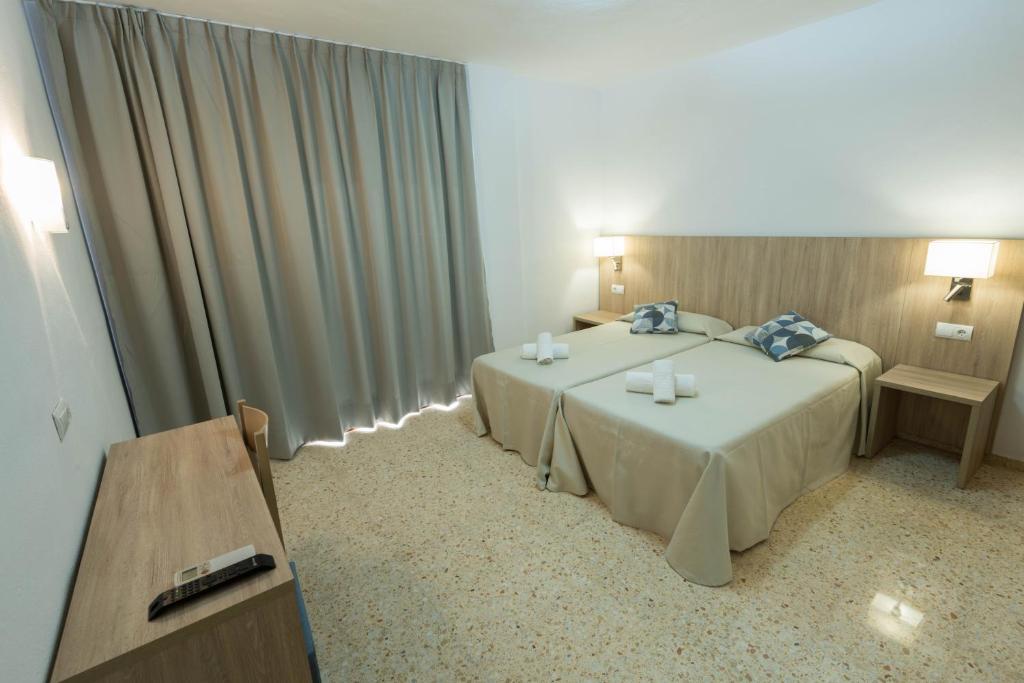 圣埃乌拉利亚梅约旅馆的酒店客房设有两张床和一张桌子。