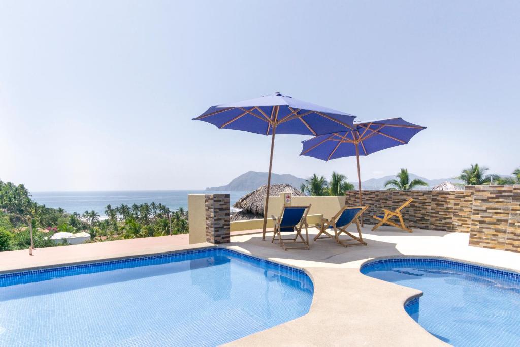 曼萨尼约Grand View Suites的一个带两把遮阳伞和两把椅子的游泳池