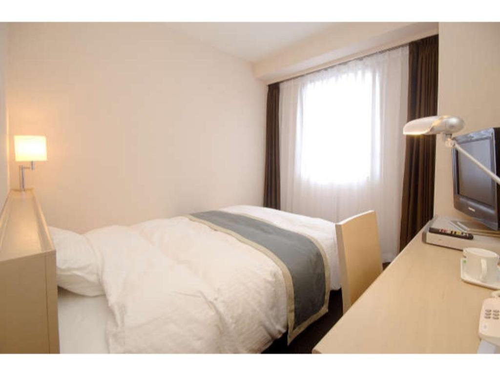 磐城Hotel Frontier Iwaki / Vacation STAY 79262的一间卧室配有一张床和一张书桌及电视