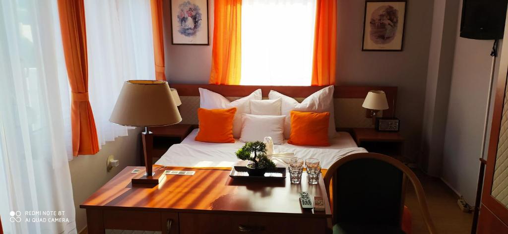希欧福克Hermina Panzió的一间卧室配有一张带橙色枕头的床和一张书桌