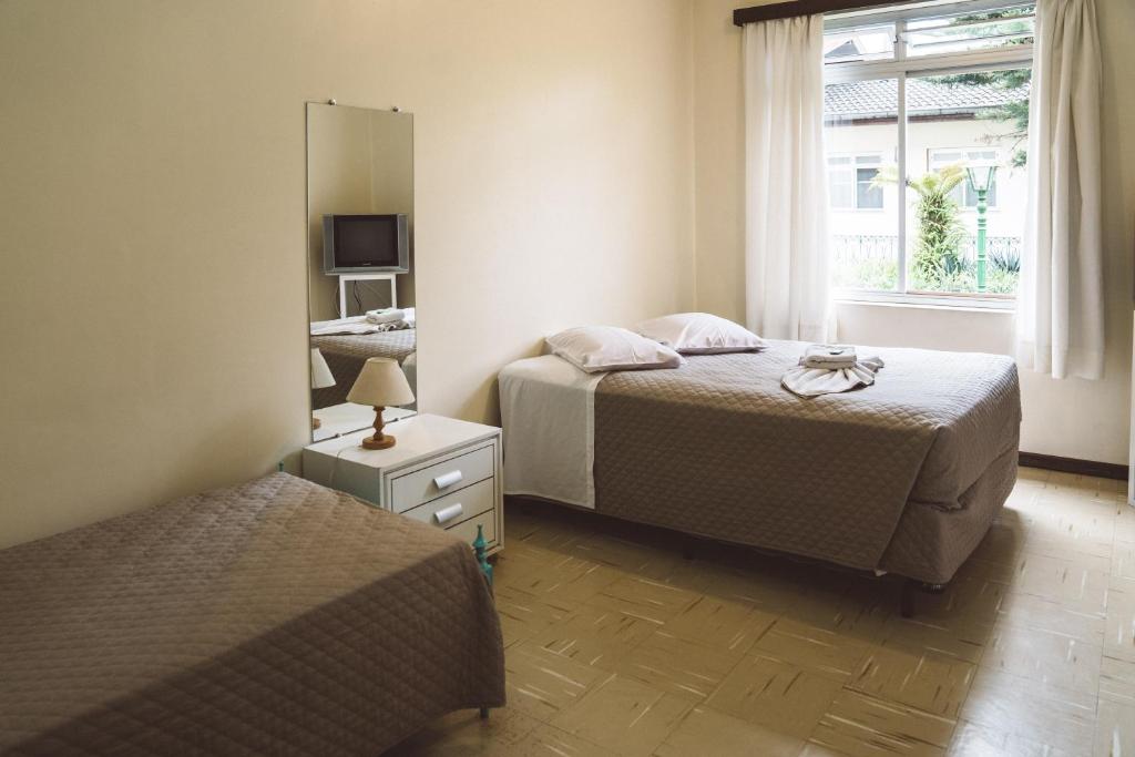 库里提巴贝塔尼亚旅馆的一间卧室配有两张床和镜子