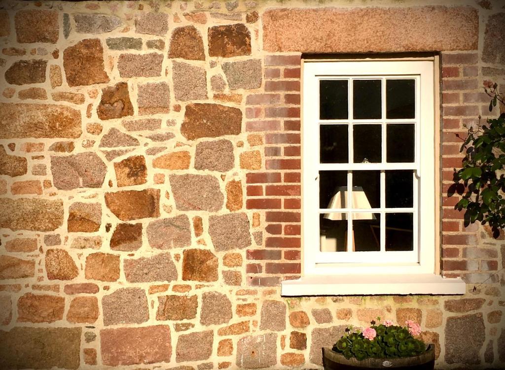 La VillaisePeaceful 2 bedroom granite country dower house的砖砌的砖砌的窗户,有盆栽植物
