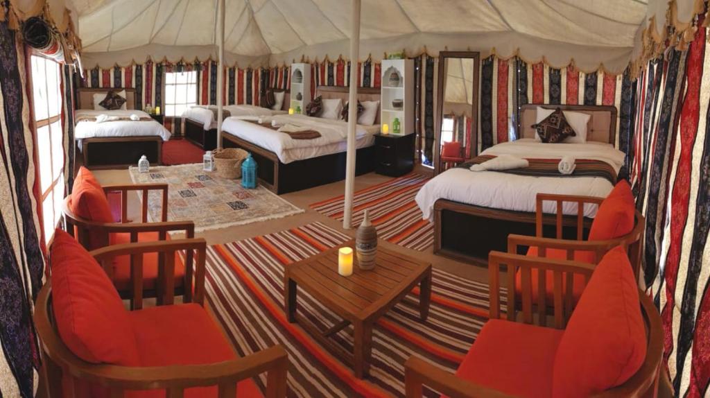 ShāhiqAlsarmadi Desert Camp的大房间设有两张床和一张桌子及椅子