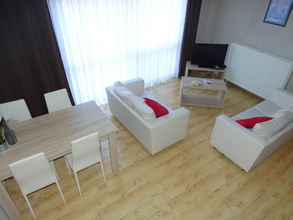 鲁汶鲁汶大使套房酒店的客厅配有桌子和白色椅子