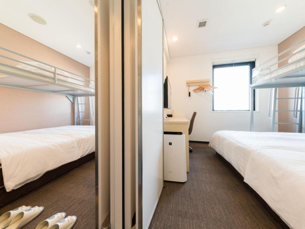 东京Super Hotel Tokyo Kinshicho Ekimae / Vacation STAY 79359的客房设有两张床、一张桌子和一面镜子。