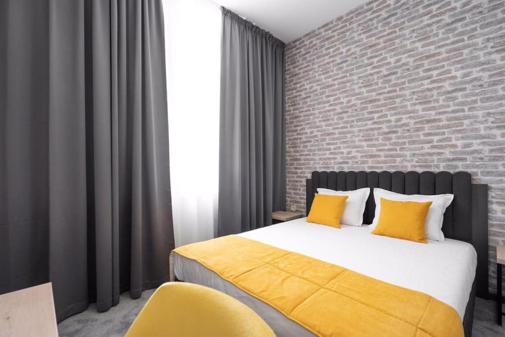 鲁塞ADEO HOTEL Sport & SPA的一间卧室配有一张带黄色枕头的床和砖墙