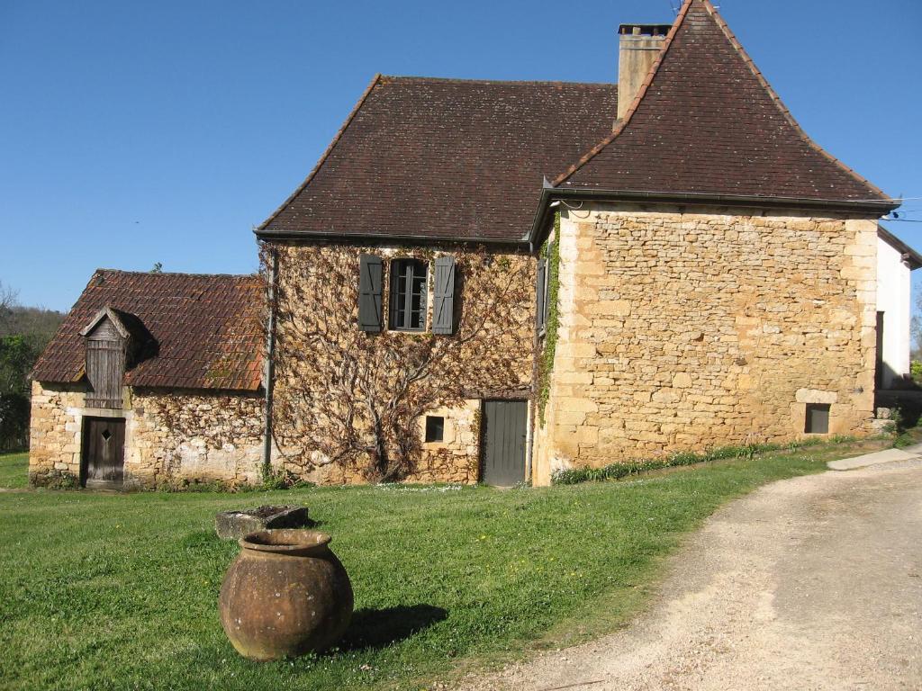 Cénac-et-Saint-JulienMAISON DE FAMILLE的一座古老的石头建筑,前面有花瓶