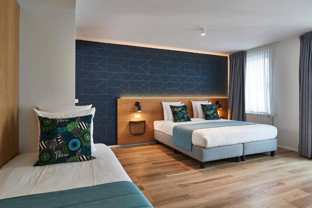 布鲁塞尔海格酒店的一间卧室设有两张床和蓝色的墙壁