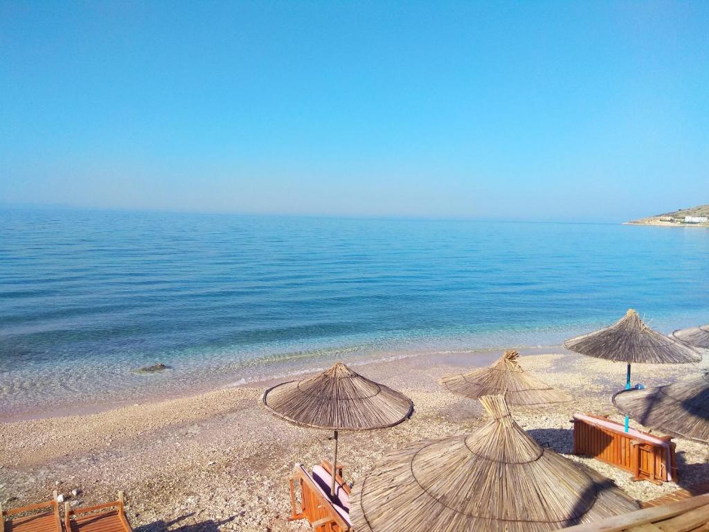 科帕罗Qeparo Pano Rooms的海滩上设有遮阳伞和椅子,还有大海