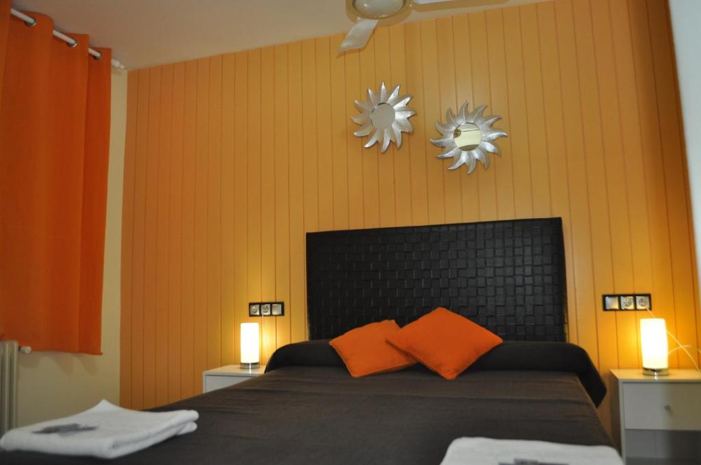 卡斯特罗·德波利亚斯Hostal Empordà的一间卧室配有一张带橙色枕头和两面镜子的床
