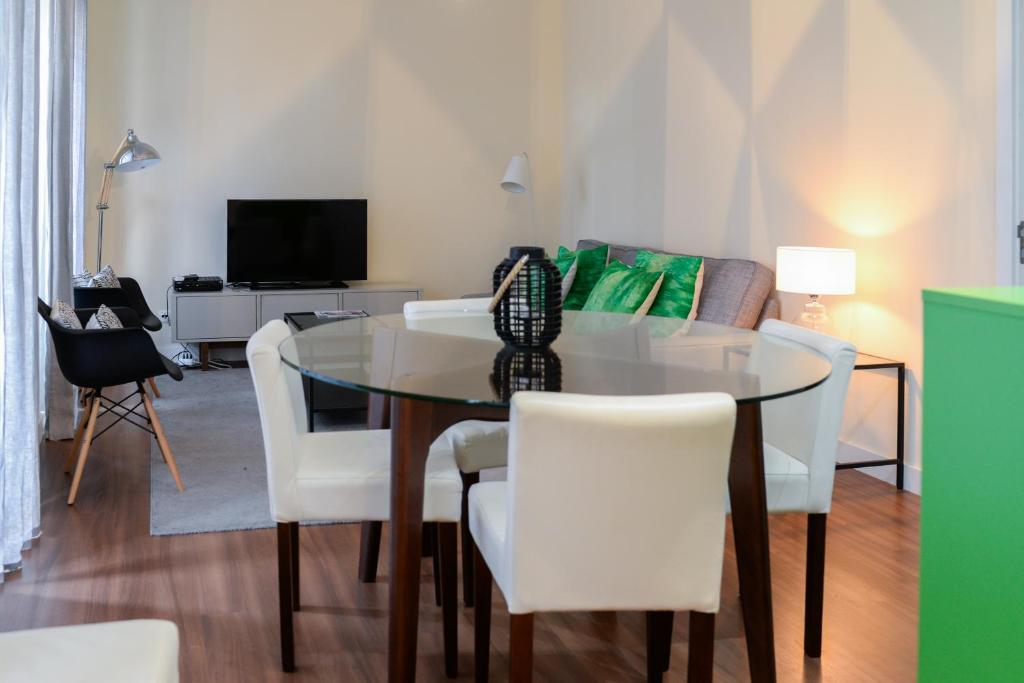 里斯本Lisbon Apartment near Marquês Pombal square的一间设有玻璃桌和白色椅子的用餐室