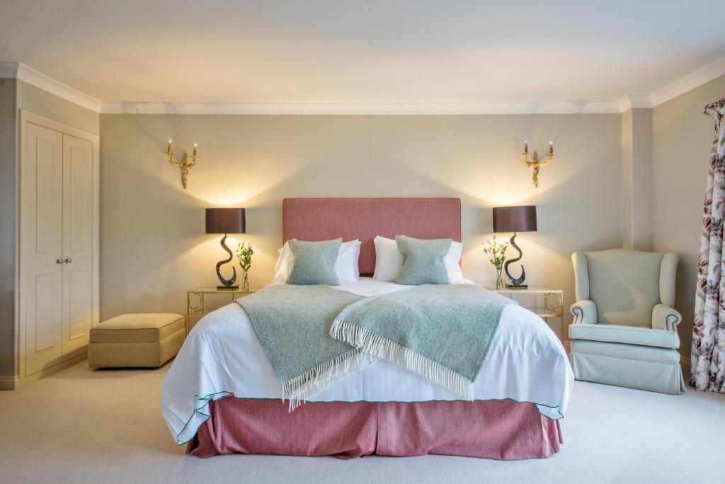 伍德斯托克马尔堡阿姆斯酒店的一间卧室配有一张大床和两把椅子