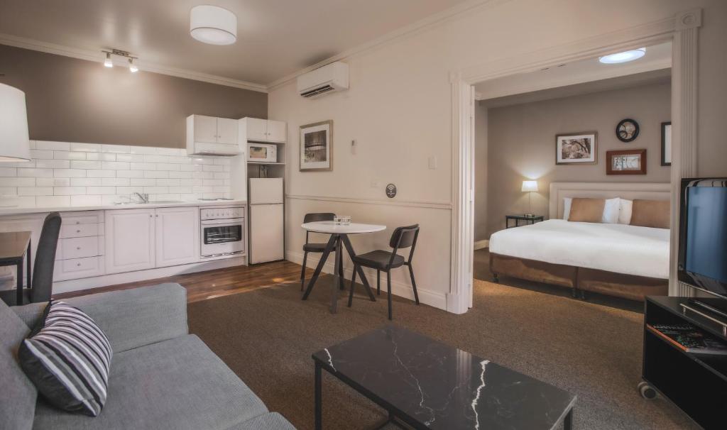 阿德莱德雄狮公寓酒店的一间带一张床的客厅和一间带沙发的房间