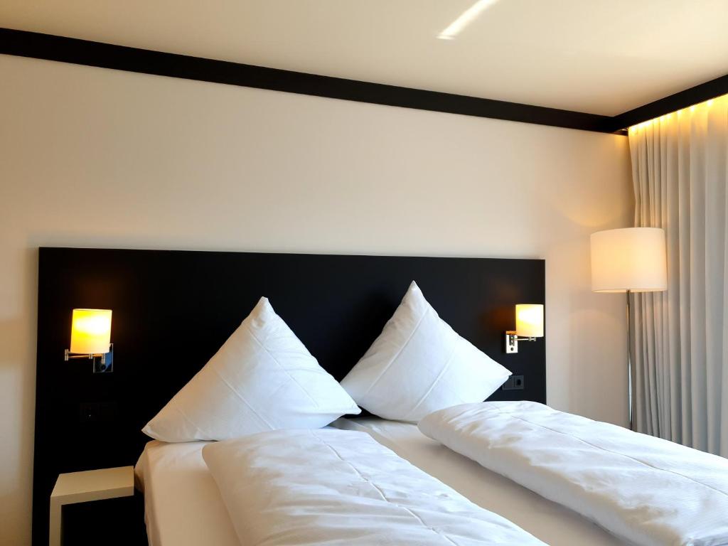 KürnachWÜ Hotel by WMM Hotels的一间卧室配有两张带白色床单和枕头的床。