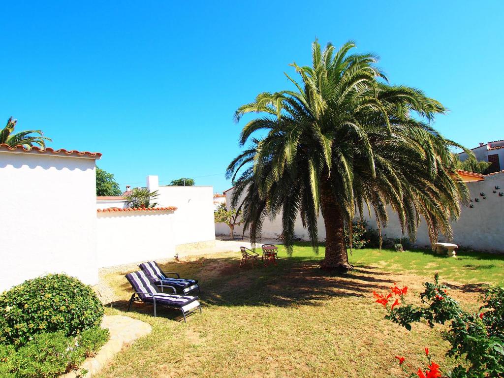 艾姆布里亚布拉瓦Villa Alberes by Interhome的院子里的棕榈树和两把躺椅