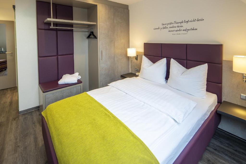 斯图加特凯莱高级酒店的卧室配有一张白色大床和黄色毯子