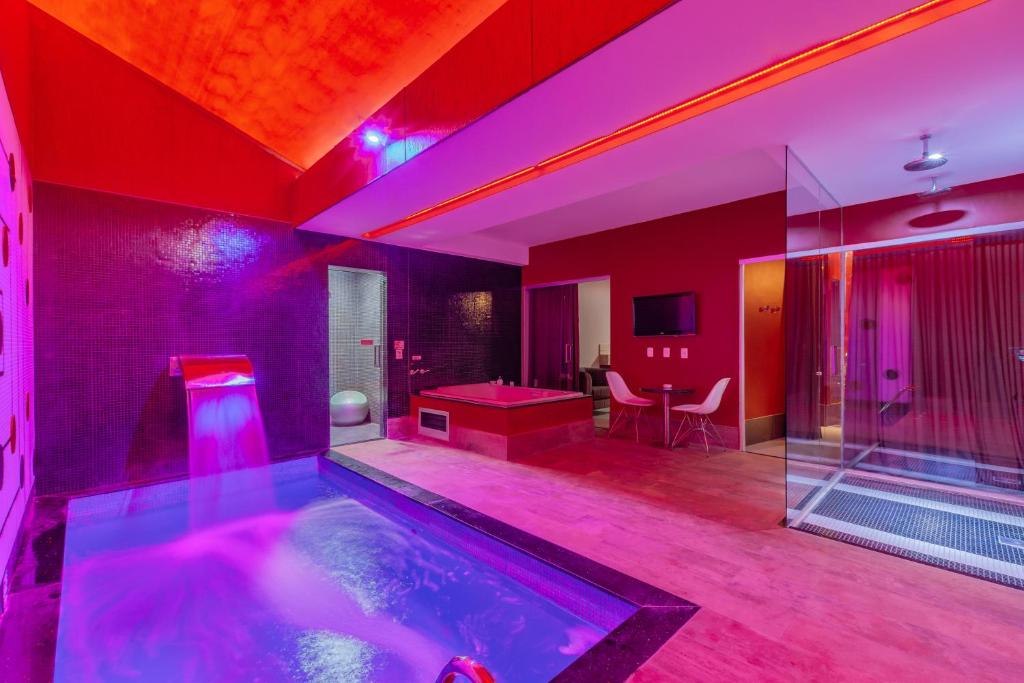 福塔莱萨阿萨依汽车旅馆（仅限成人）的一间设有紫色照明的游泳池的客房