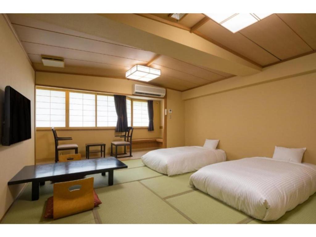 仙北Tazawako Lake Resort & Onsen / Vacation STAY 78936的一间设有两张床和一张桌子及椅子的房间
