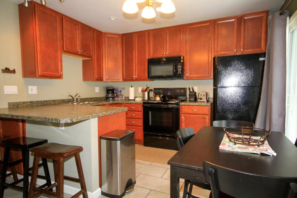 马姆莫斯湖Sierra Park Villas #65的厨房配有木制橱柜和黑色冰箱。