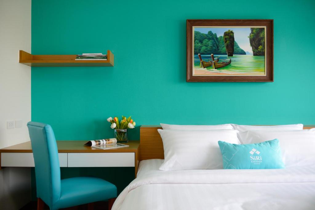 曼谷曼谷斯瑞拉哈达酒店的一间卧室设有蓝色的墙壁、一张床和一张书桌