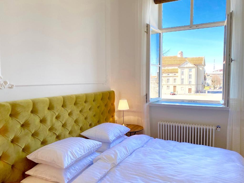 利耶帕亚Glamour apartment的一间卧室配有一张带黄色床头板的床和窗户