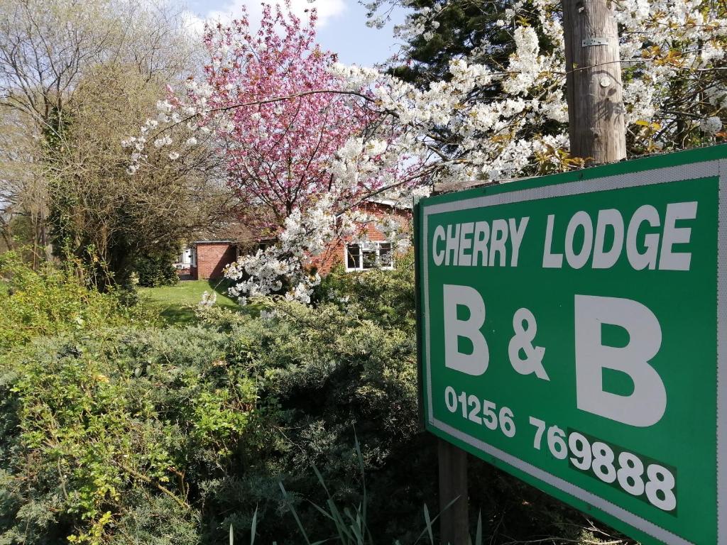 胡克Cherry Lodge的樱桃小屋的绿色标志,背景是房子