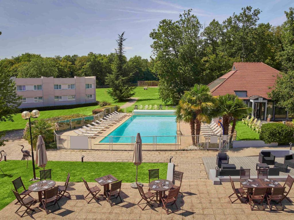 尤里枫丹白露尤里诺富特酒店的一个带桌椅的户外庭院和一个游泳池