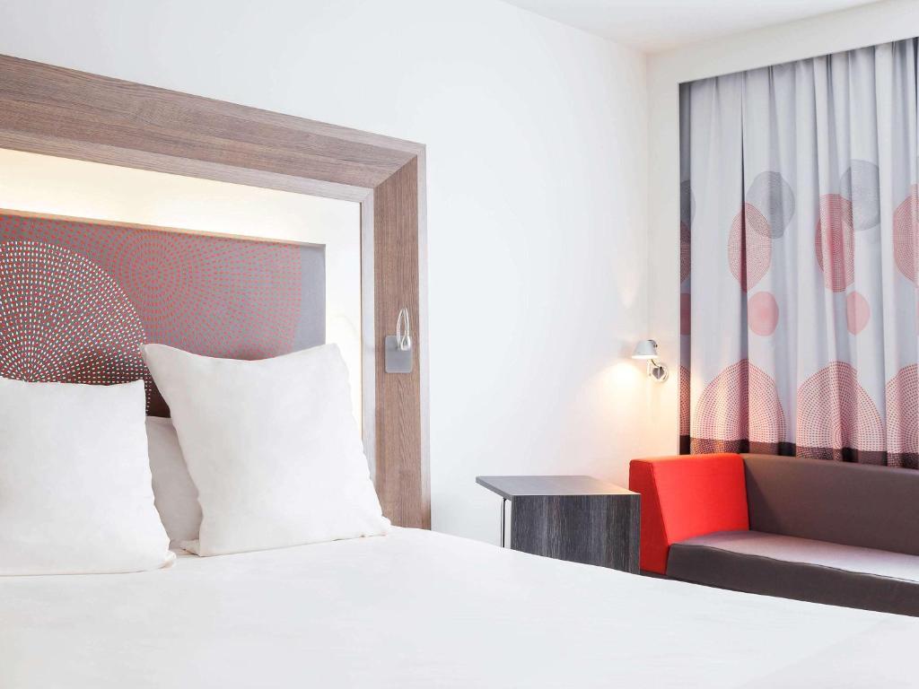 莱斯坎诺沃特里尔机场酒店的一间卧室配有一张床和一张红色椅子