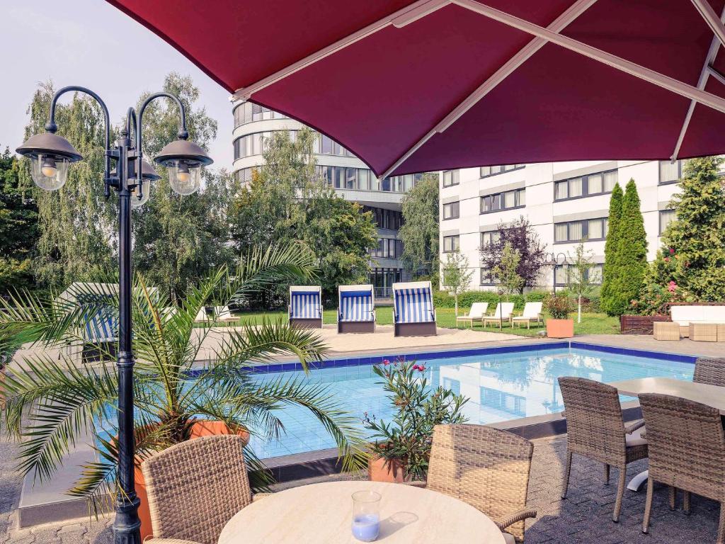 埃施伯恩法兰克福艾许柏恩奥斯特美居酒店的游泳池旁带遮阳伞的桌子