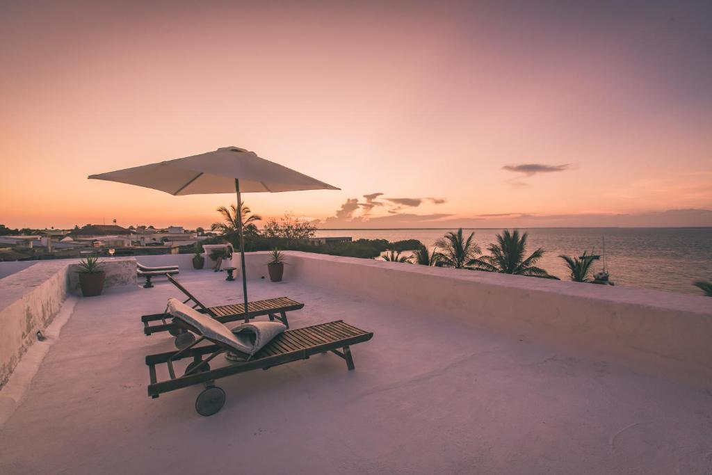 莫桑比克岛Terraço das Quitandas Design Accommodation-AL的一个带2个长椅和遮阳伞的庭院和大海