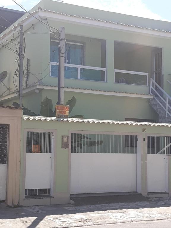 里约热内卢Quarto com banheiro para solteiros no Rio de Janeiro的白色的房子,设有两个车库门和阳台