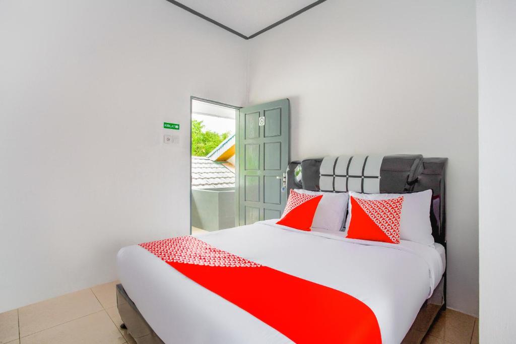 武吉丁宜OYO 2903 Putri Residence Syariah的一间卧室配有红色和白色枕头的床