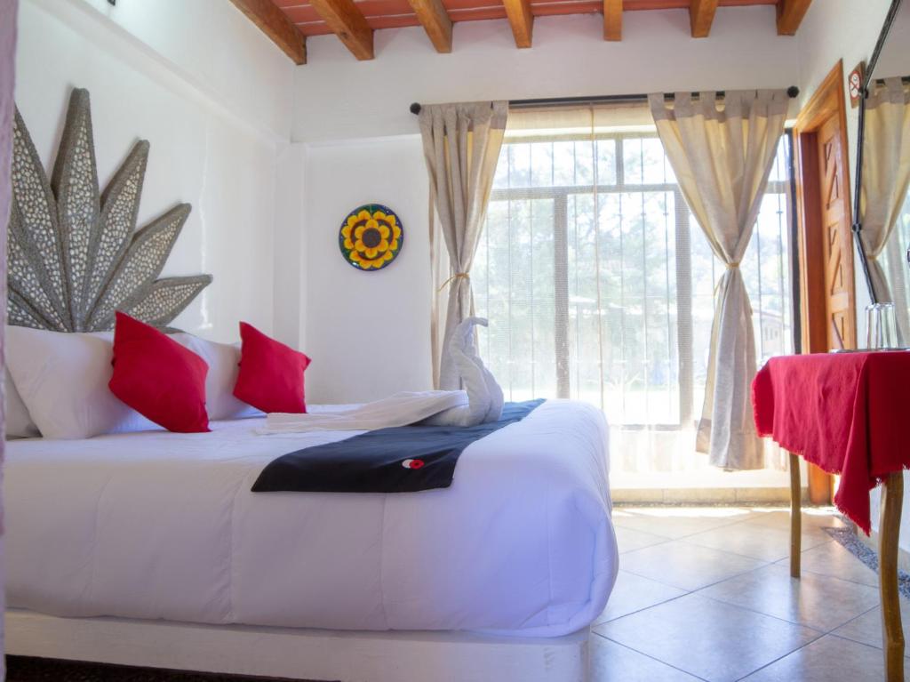 巴耶德布拉沃Valle Dorado的卧室配有白色的床、红色枕头和窗户