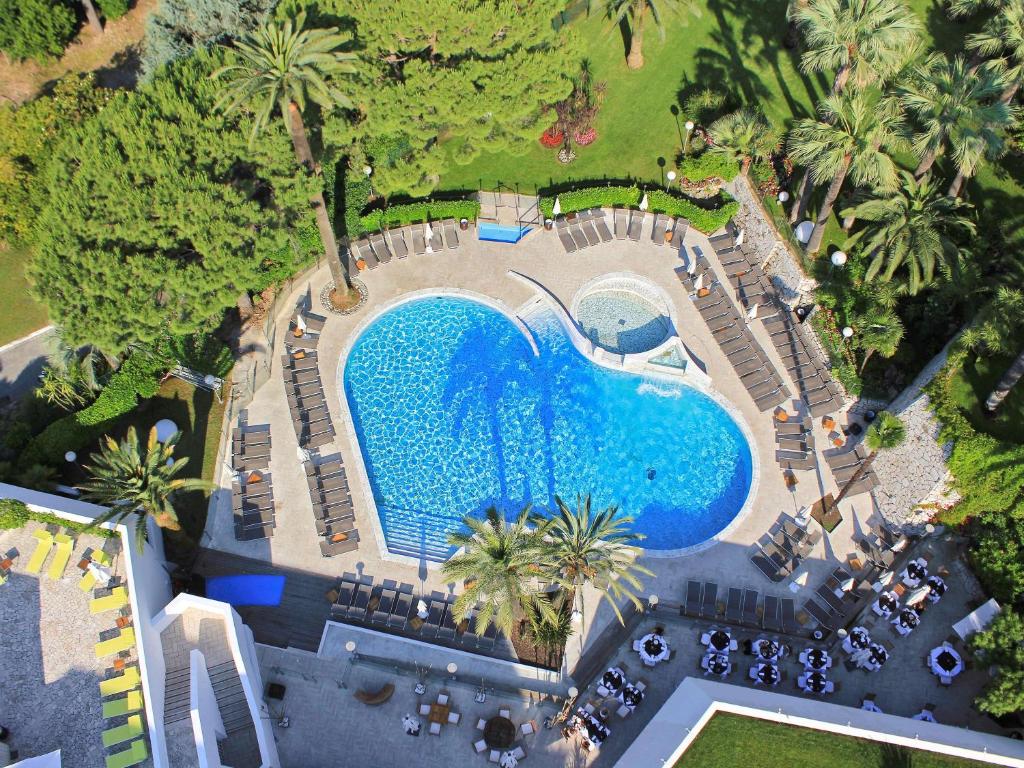 戛纳Hotel Cannes Montfleury的享有带椅子和棕榈树的游泳池的顶部景致