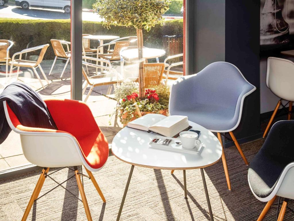 卢顿伦敦卢顿机场宜必思酒店的一组椅子和一张桌子,上面放着一杯咖啡