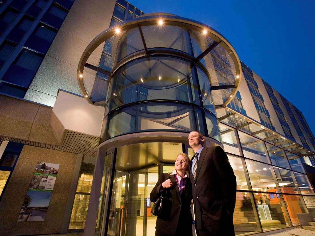 格拉特布鲁格诺富特苏黎世机场会展中心酒店的两个人站在一座建筑前面