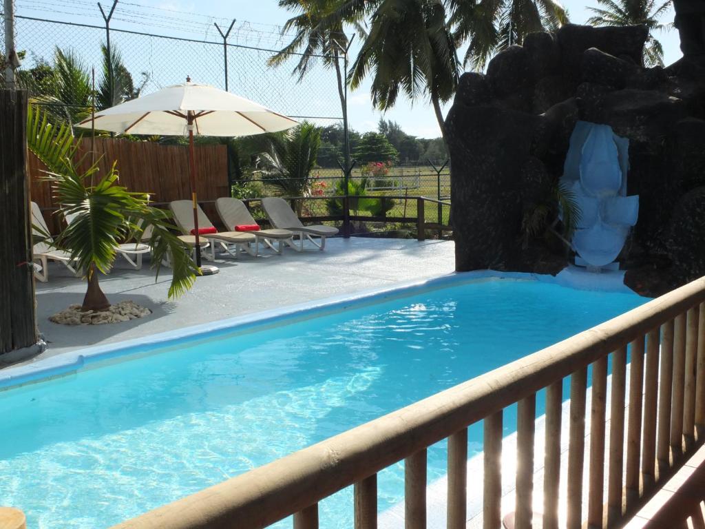 贝尔马尔伊甸园别墅酒店的一个带遮阳伞的围栏上的游泳池