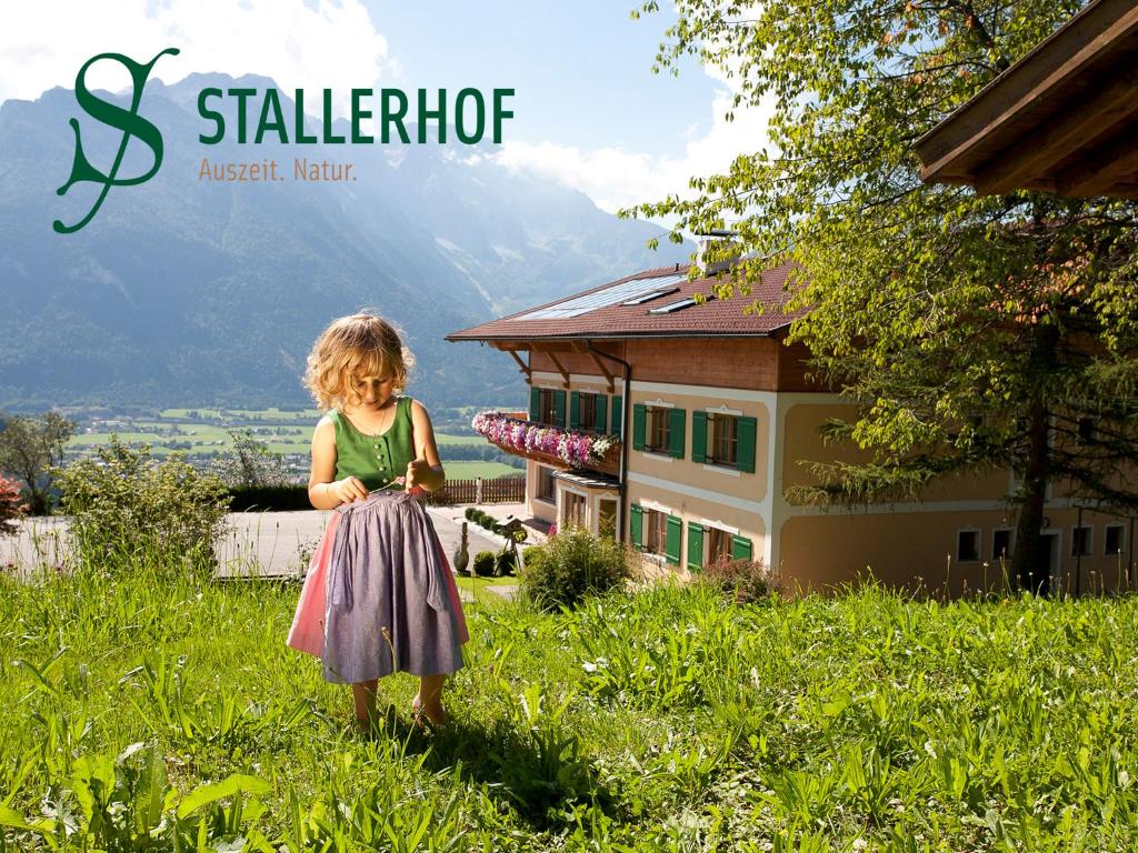萨尔察赫河畔戈灵斯塔勒贺夫酒店的站在房子前面的草上的小女孩