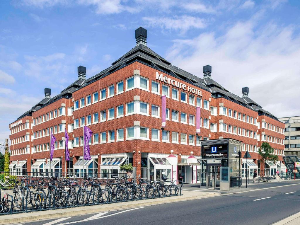 科隆科隆瑟夫灵霍夫美居酒店的一座大型砖砌建筑,前面停放着自行车