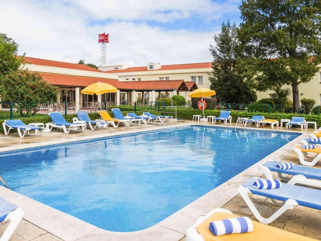 塞图巴尔塞图巴尔宜必思酒店的一个带椅子和遮阳伞的游泳池