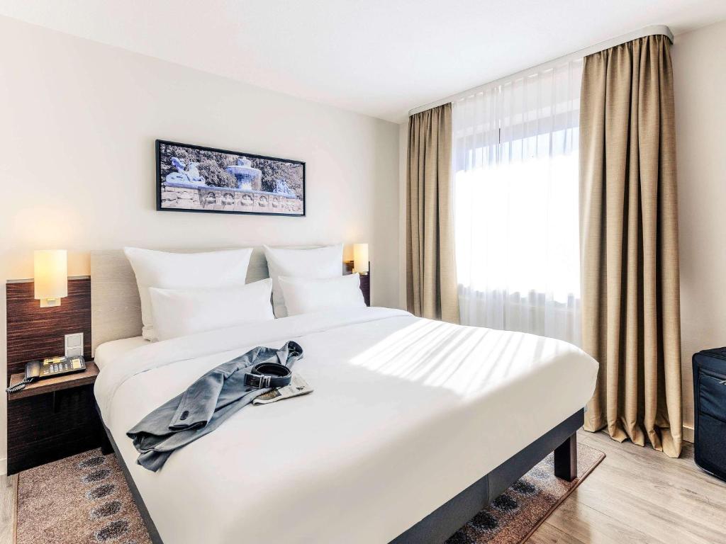 慕尼黑美居酒店南慕尼黑展览会店的一张大白色床,位于酒店带窗户的房间内