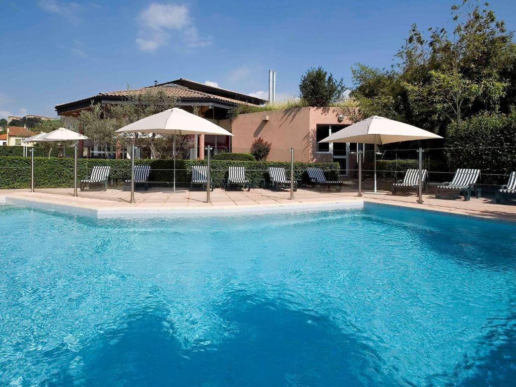 欧布纳奥贝纳斯宜必思酒店的一个带椅子和遮阳伞的大型蓝色游泳池