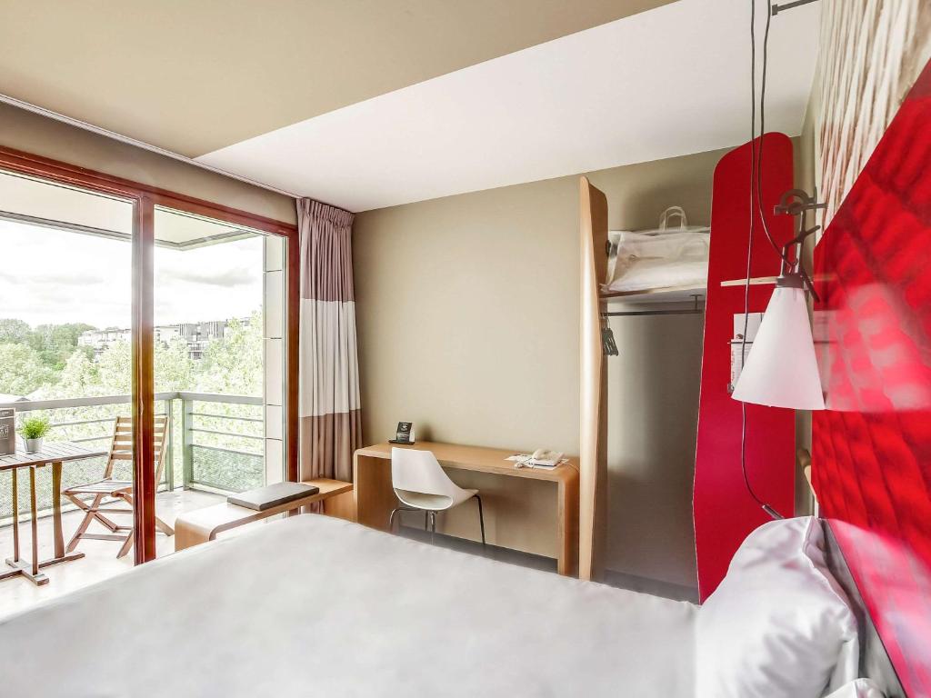 巴黎宜必思巴黎贝尔西村酒店的酒店客房设有一张床、一张书桌和一个阳台。