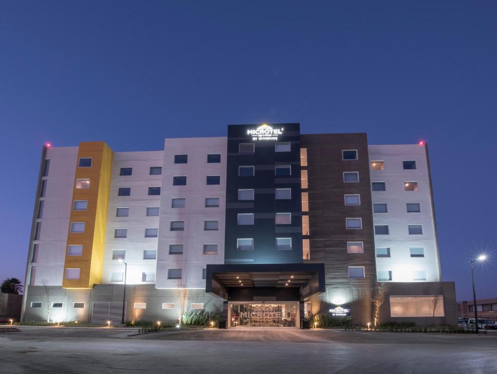 伊拉普阿托Microtel Inn & Suites by Wyndham Irapuato的夜间酒店大楼,设有停车场