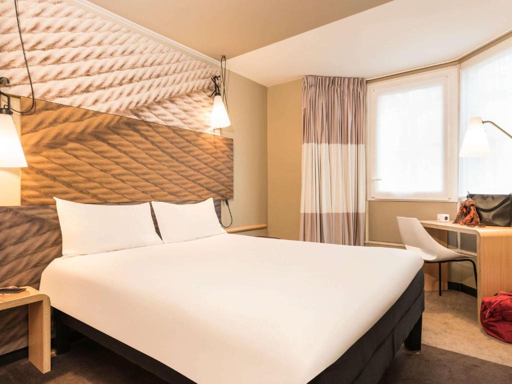 巴黎朗东堡10号巴黎北站宜必思酒店的酒店客房设有一张大床和一张书桌。