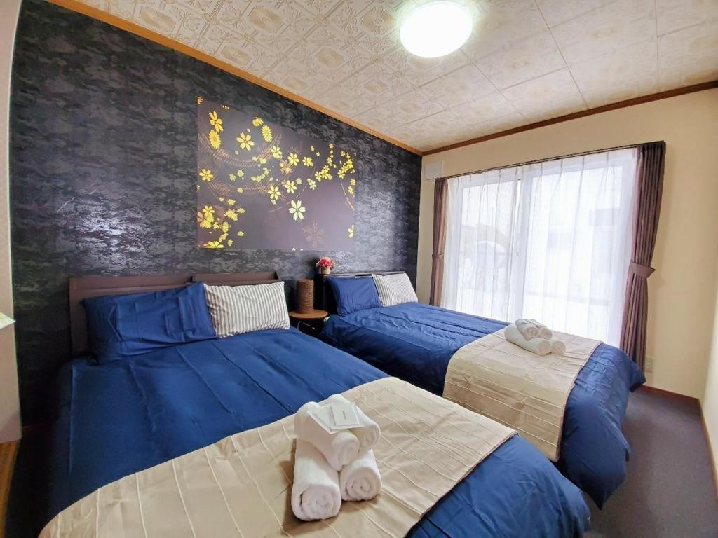 旭川旭川ファミリーハウスみんみん的卧室设有两张床铺,配有蓝色床单