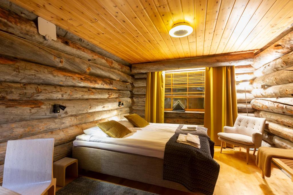 萨利色尔卡Kuukkeli Log Houses Teerenpesä的一间卧室设有一张床和木墙