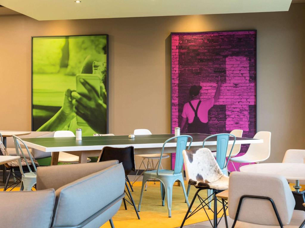 苏黎世苏黎世展览中心机场宜必思酒店 的一间设有桌椅的房间和墙上的绘画