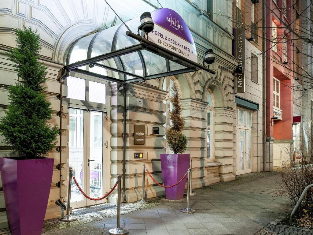 柏林美居酒店柏灵查勒边检站店的建筑上的一个标志,上面有两根大紫花瓶